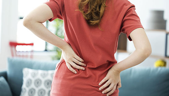 Woman holding lower back in pain before visiting San Ramon chiropractor