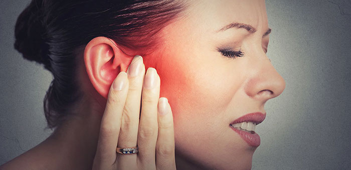 Woman holding her ear in pain due to ear infection before visiting San Ramon chiropractor