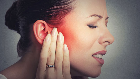 Woman holding her ear in pain due to ear infection before visiting San Ramon chiropractor